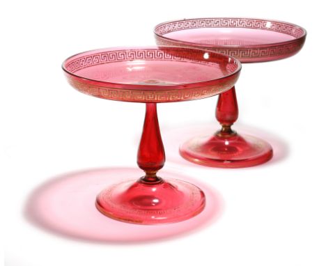 A matched pair of Victorian ruby glass tazze, with gilt Greek key bands, each with a baluster stem and a domed foot, 19.5cm h