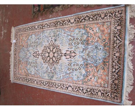 An Indian silk carpet circa 1960s, pale blue central medallion on an orange ground. 181cm x 95cm.