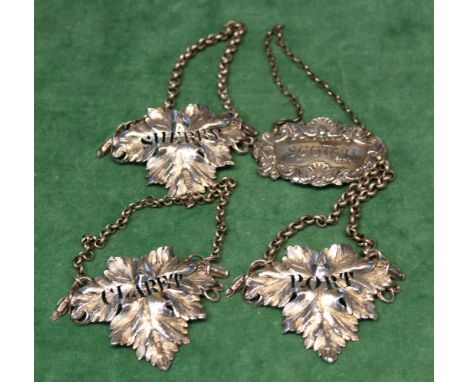 A set of three Victorian silver decanter labels of leaf form and a silver 'scotch' label