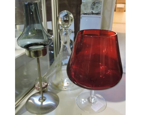 A 1970's  flared glass decanter and stopper, an oversized cranberry-coloured wine glass, an aluminium tealight holder with bl