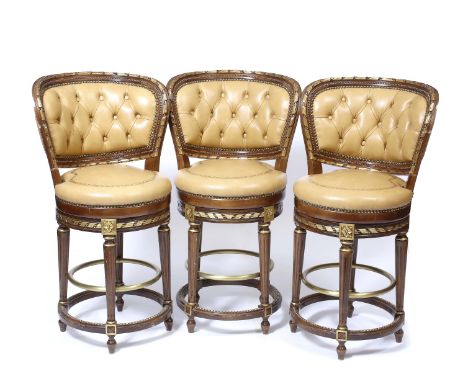 A SET OF THREE FRENCH STYLE ROTATING HIGH STOOLS with parcel gilt hardwood frames and tan leather button upholstered back and