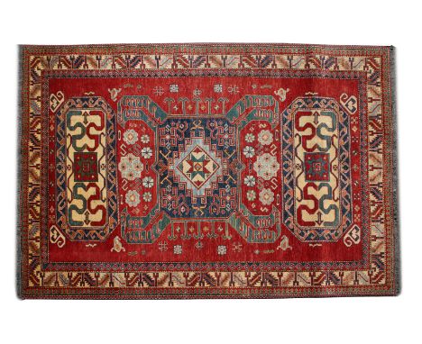 A MODERN KAZAK RED GROUND SMALL CARPET with stylised geometric decoration within a banded border, 180cm x 260cm 