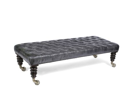 A BLACK LEATHER BUTTON UPHOLSTERED LONG LOW RECTANGULAR STOOL with turned carved mahogany legs and brass casters, 166cm long 