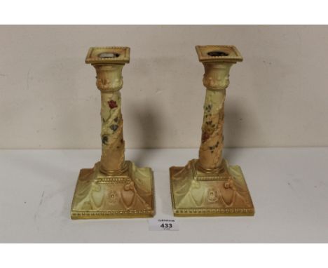 A PAIR OF ROYAL WORCESTER BLUSH IVORY CANDLESTICKS, decorated with hand painted floral and raised gilt detail, printed marks 