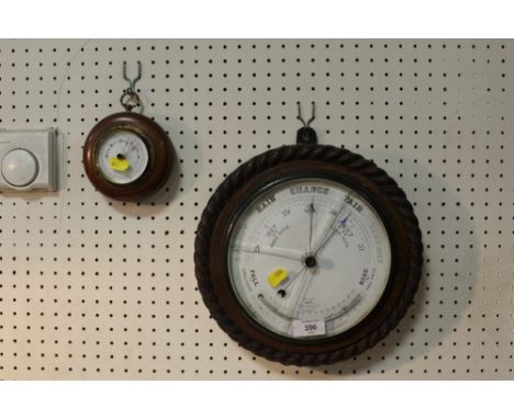 A CARVED OAK CIRCULAR WALL BAROMETER TOGETHER WITH A SMALLER EXAMPLE (2)