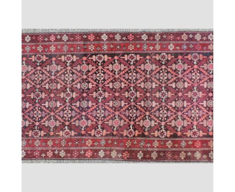 A Persian carpet, with geometric designs on a red ground, 435 x 114cm 