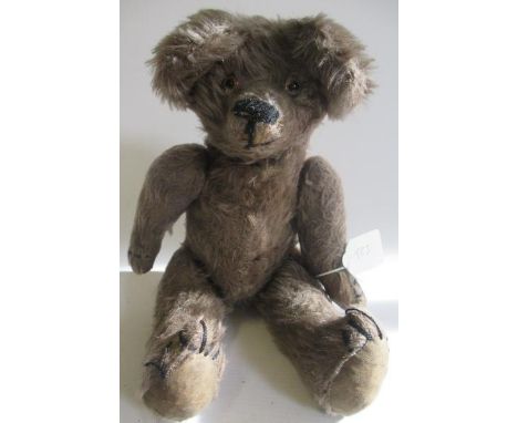 An old teddy bear, with light brown plush, glass eyes, sewn nose, large ears, hump and fabric pads, 15" long (Est. plus 21% p