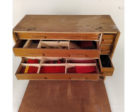 A vintage wooden chest with multiple drawers and Meccano contents