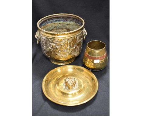 A brass coal bucket with impressed cottage scenery, a lion head wall plaque and a brass and copper container on tripod base.