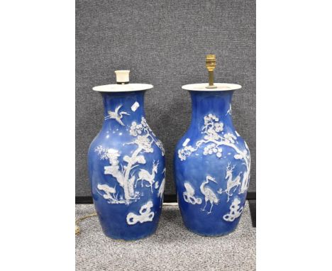 A pair of antique Qing dynasty mirrored floor vase having a reverse blue and white embossed decoration of a deer and stalk be