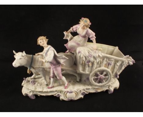 Two continental bisque figurines of a cow pulling a cart alongside two figures