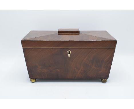 19th century mahogany tea caddy in a sarcophagus form mounted on brass ball feet. In good condition with some minor splits to