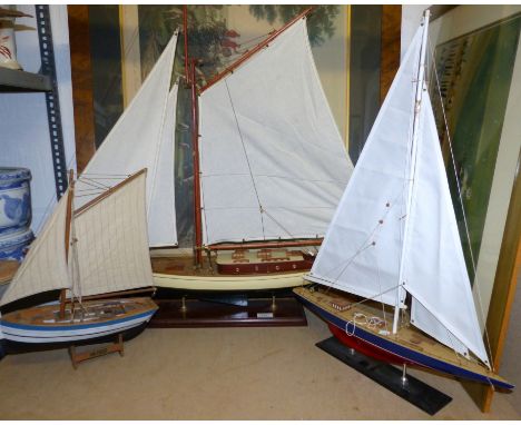 A wooden model yacht on plinth, overall height 34"; another; a similar model fishing boat