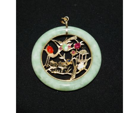A modern circular jade coloured oriental pendant  with a centrally pierced landscape set with coloured stones, the loop stamp