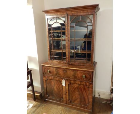 A George IV mahogany secretaire library bookcase, having a plain moulded cornice, above a pair of arched bar glazed doors, en