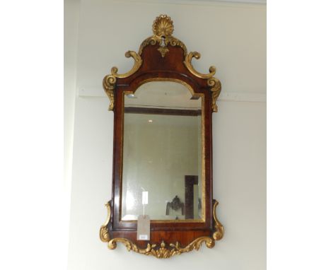 A George II walnut and parcel gilded chimney glass, of cartouche form, surmounted by foliate scrolls and a scallop shell abov
