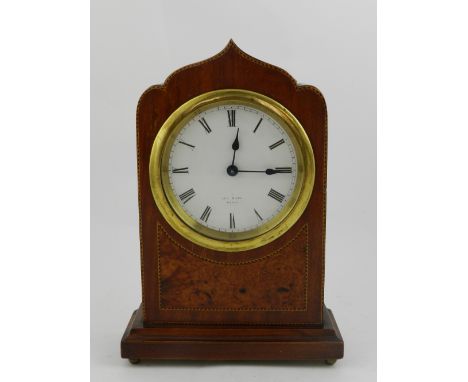 An early 20th century mantel clock, of rectangular form and shaped top, the dial yellow metal mounted above walnut inlaid ape