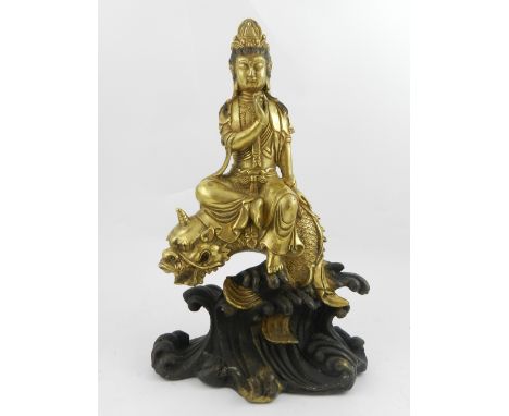 A Chinese bronze figural study of a Buddha on a dragon fish, raised upon stylised waves. H.30cm 