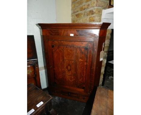 An early George III North Country oak hanging corner cupboard, mahogany cross banded and marquetry inlaid, the cupboard door 