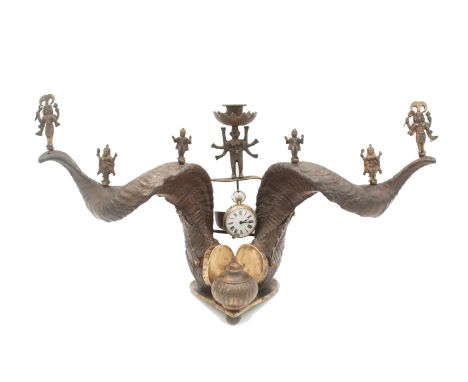 An Anglo-Indian ram's horn desk stand, the horns surmounted by metal figures of gods and central candleholder, above a hangin