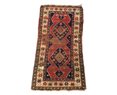 A Kazak rug, South West Caucasus, the madder field with indigo medallions filled with rosettes and guls, within an ivory rose