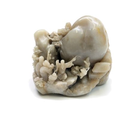 A Chinese white and greyish tinted soapstone boulder pierced and carved as a mountain range dominated by a large plain mounta