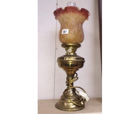 A brass oil lamp with amber glass shade