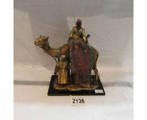 A painted metal figure group of carpet sellers with camel.