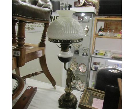 A cast iron figural oil lamp with white glass font and shade.