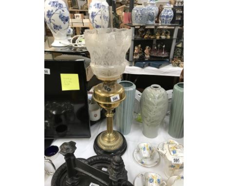 A brass oil lamp with etched shade