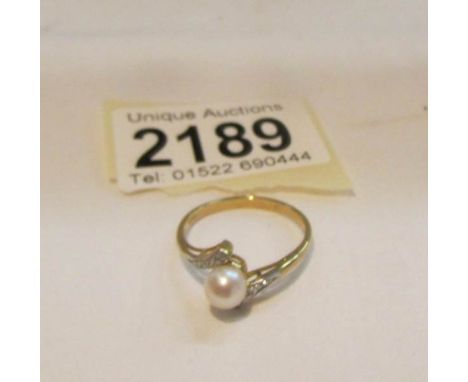 A 9ct gold ring set pearl and shoulder diamonds.