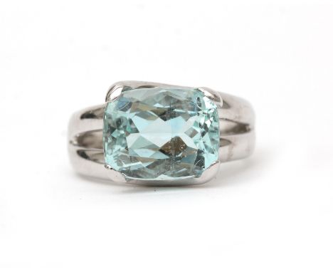 An 18 karat white gold aquamarine solitaire ring. Featuring a cushion cut light blue aquamarine of ca. 3.85 ct. in a cross ov