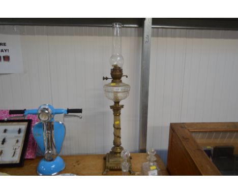 A gilt metal mounted oil lamp with clear glass reservoir and chimney