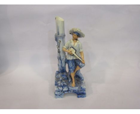 A late 19th/early 20th Century Continental porcelain figural vase as a young man seated on a tree stump on a bridge, playing 