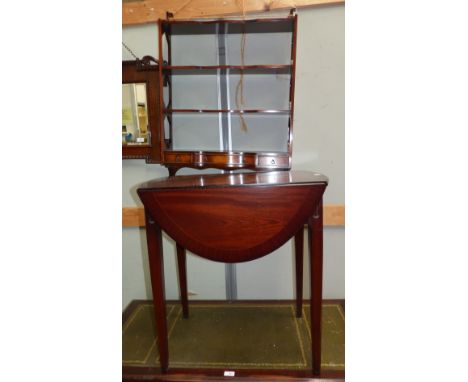 A reproduction oval Pembroke table in crossbanded mahogany; a mahogany reproduction 4 height wall shelf unit with drawers und