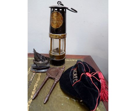 A Hailwoods improved minors lamp, a small silvered ship, an oriental handheld guillotine device and a cap