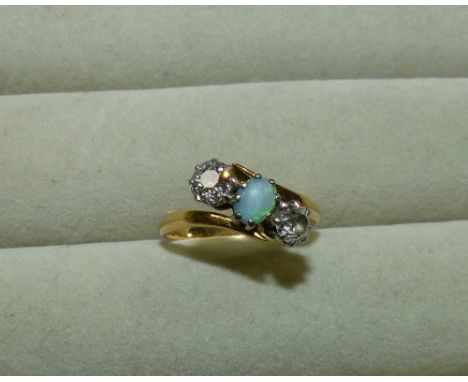 A ladies dress ring set an opal and 2 diamonds, yellow metal shank