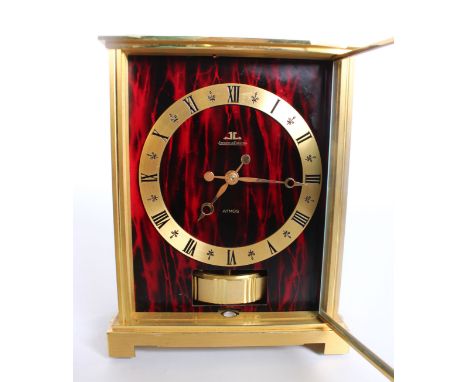 A Jaeger Le Coultre Atmos clock, Embassy, signed Jaeger LeCoultre, circa 1975, with red and black faux marble panels, base wi