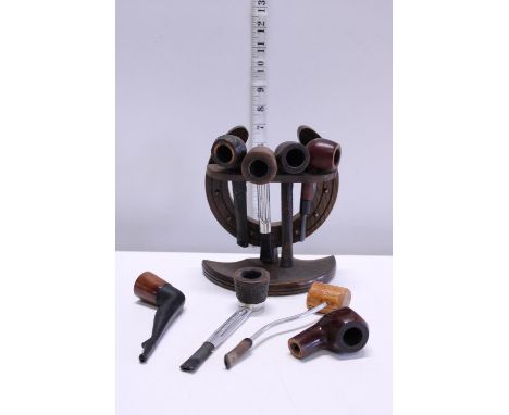 A vintage wooden pipe rack and selection of assorted pipes 