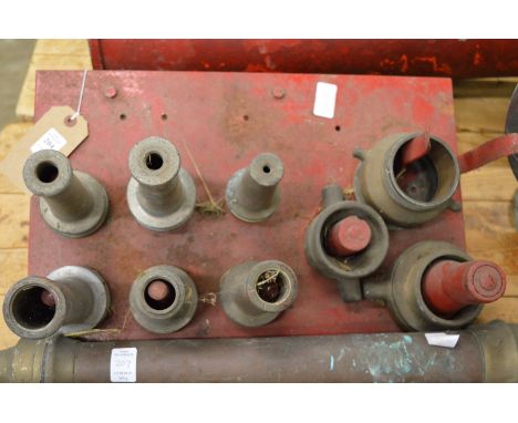 A wall mounted bracket housing numerous fireman's hose tips.