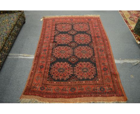 A Persian rug, red ground with two rows of four medallions, 200cm x 130cm.