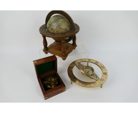 A brass compass marked Nauticalia London contained in wooden case, a brass desk compass and a desktop terrestrial globe.