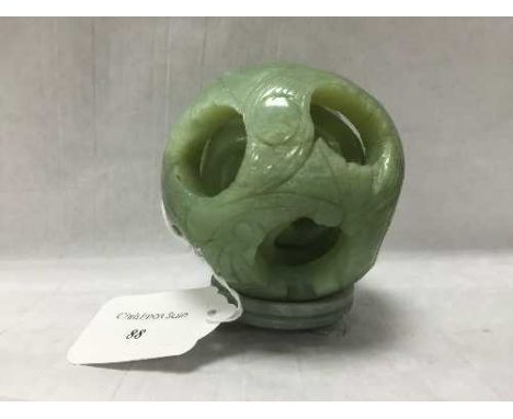 A carved jade puzzle ball on stand, diameter 9 cm. CONDITION REPORT: Good condition.
