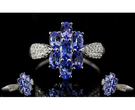 Tanzanite Cluster 9ct White Gold Ring with natural white zircon accent shoulders, the centrepiece comprising seven oval cut t
