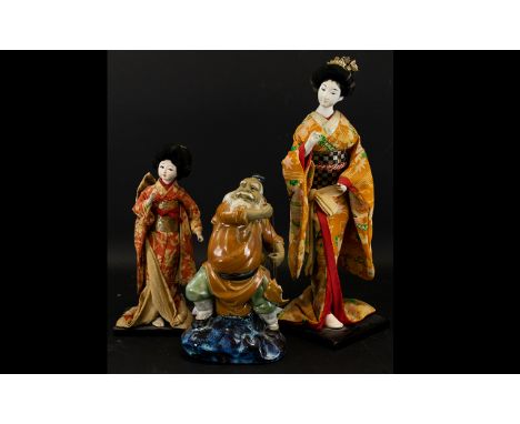 A Pair of Mid 20th Century Japanese Deity Doll Figures Each on wood stands, together with a ceramic Chinese fisherman figure.
