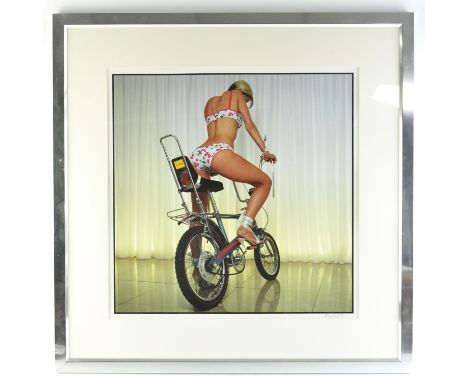 A print of Kate Lawler posing on a Raleigh Chopper, indistinctly signed in pencil, 50 x 50cm, framed and glazed. 