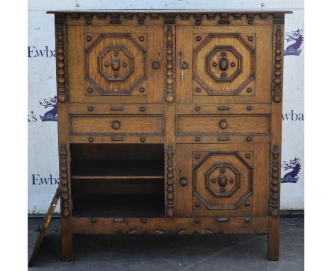 A Tudric style oak cabinet of four cupboards and two drawers, 130cm high, 121cm wide, 51cm deep.