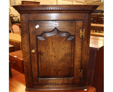 An 18th Century style oak corner cupboard with dentil moulded cornice, the ogee fielded panel door enclosing a shelf 65cm hig