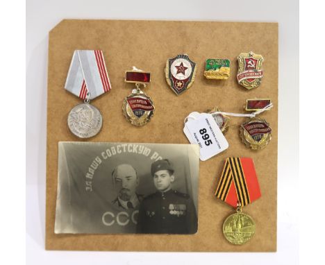 A mounted collection of Russian medals and enamel badges &amp; a postcard Condition Report: Available upon request