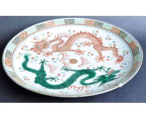 A 19th Century Chinese large porcelain charger plate. Depicts two dragons in ochre and verte with central pearl. Repeating ke